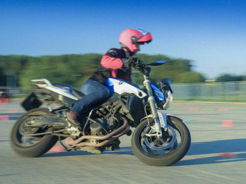 Motorradfahrerin übt Kurventechnik und Schräglage auf einer BMW bei einem Fahrsicherheitstraining.